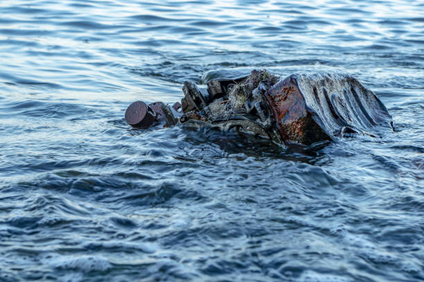 istock Old rusty engine lying among stones in the water 1179676142