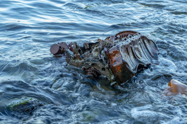 istock Old rusty engine lying among stones in the water 1179676370