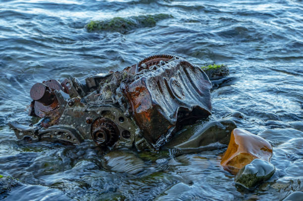 istock Old rusty engine lying among stones in the water 1179676374