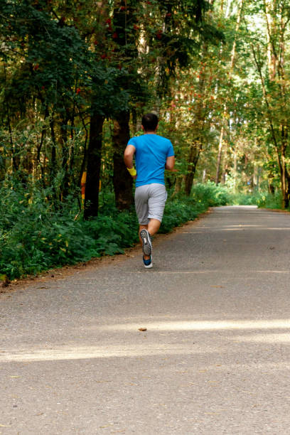 istock Young active handsome male healthy runner jogging outdoors along a scenic path in a forest. Vertical shot. 1179679094