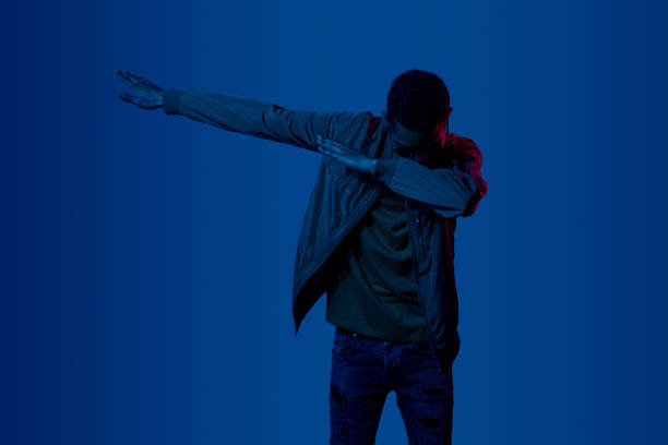 Black man making dab movement African American male in casual outfit dabbing under red neon light against dark blue background dab dance photos stock pictures, royalty-free photos & images