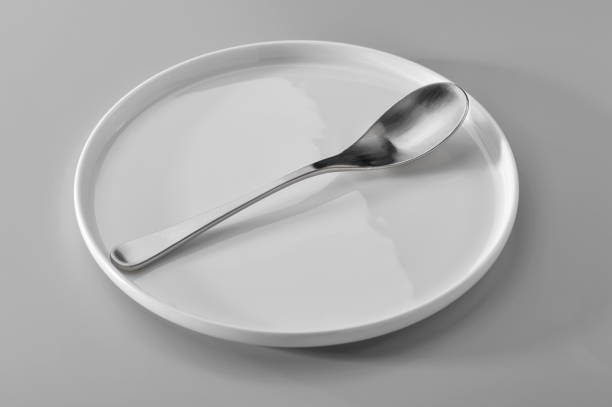 istock spoon on white plate against neutral gray background 1179684117