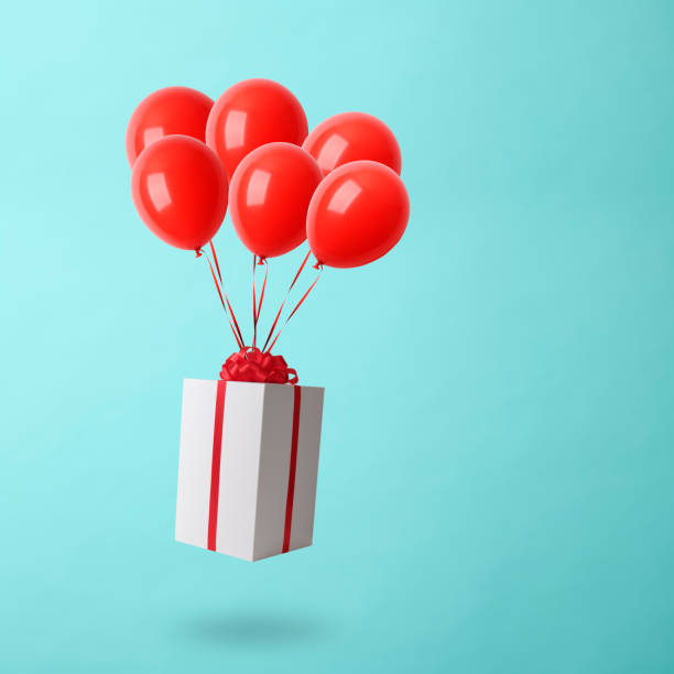 istock Christmas gift box with balloons in mid-air against light blue background 1179689268