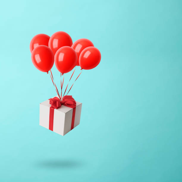 istock Christmas gift box with balloons in mid-air against light blue background 1179689269