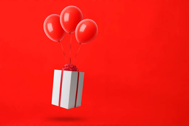 istock Christmas gift box with balloons in mid-air against red background 1179689913
