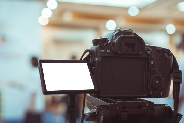 istock Video or professional digital dslr with blank lcd on tripod for camera recording taking photograph in production house or convention hall in live streaming event, media meeting  broadcast equipment. 1179694871