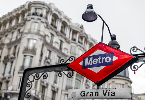 Madrid, Spain - June 4, 2017: Traditional red and blue metro sign for the Gran Via station in the city center shopping area, selective color treatment