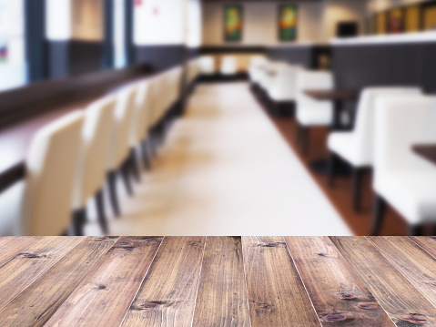 Wood table top over abstract blur background of cafe or restaurant interior. Montage style to dispaly the product.