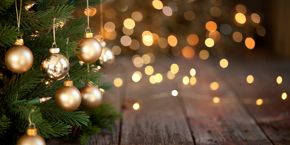 Christmas tree with gold baubles and lights against an old wood background