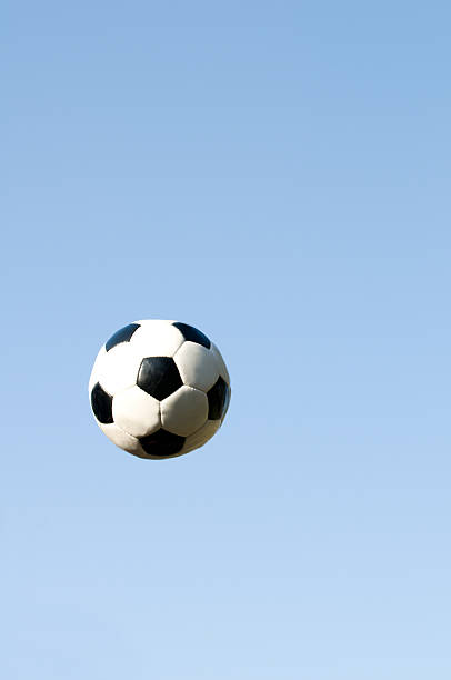 istock Soccer ball flys through the air on clear blue sky 117971383