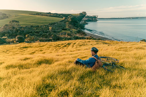 Professional road cyclist sit on the open field watch sunset