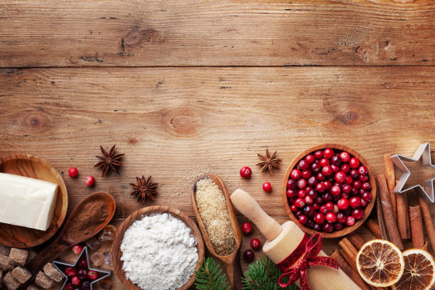 Bakery background with ingredients for cooking Christmas baking. Flour, brown sugar, butter, cranberry and spices on wooden table top view. Bakery background with ingredients for cooking Christmas baking. Flour, brown sugar, butter, cranberry and spices on wooden table top view with copy space. winter food top view stock pictures, royalty-free photos & images