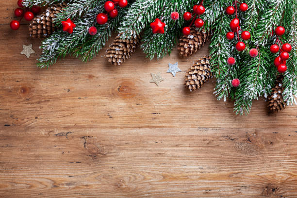Christmas background. Snowy fir tree branches with fir cones and red berries on wooden board. Top view with space for text. Christmas background. Snowy fir tree branches with fir cones and red berries on wooden board. Top view with space for text and design. evergreen tree photos stock pictures, royalty-free photos & images
