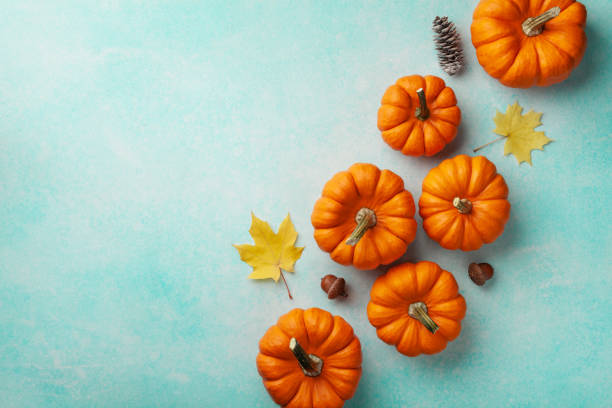 istock Autumn Thanksgiving background. Pumpkins and maple leaves on turquoise table top view. 1179720833