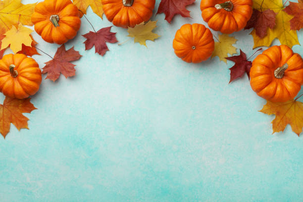 istock Autumn Thanksgiving background. Pumpkins and maple leaves on turquoise table top view. 1179720868