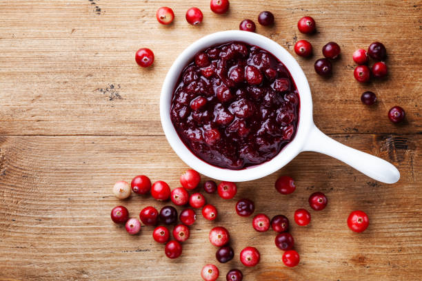 istock Cranberry sauce in ceramic saucepan with berries on wooden kitchen table from above. 1179720879