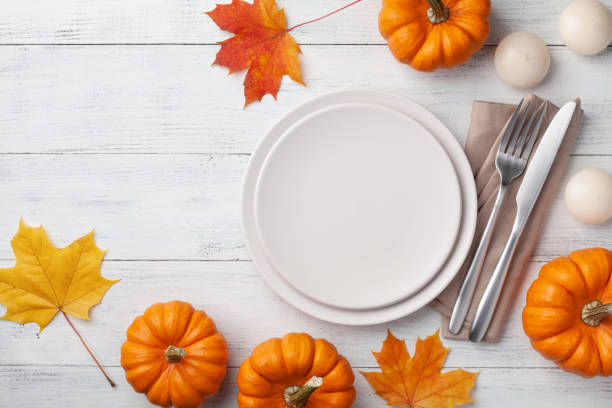 istock Autumn Thanksgiving table setting for dinner with plate, knife, fork decorated pumpkins and maple leaves top view. 1179720912