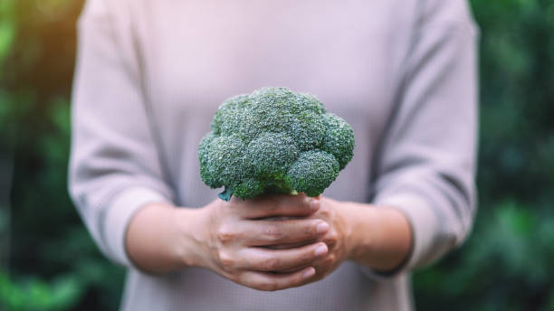 istock a woman holding a green broccoli 1179722172