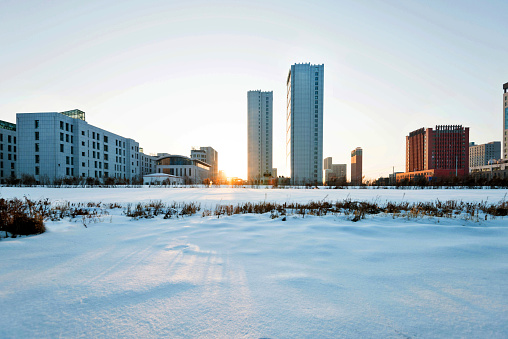 Snow land and city buildings in sunset.