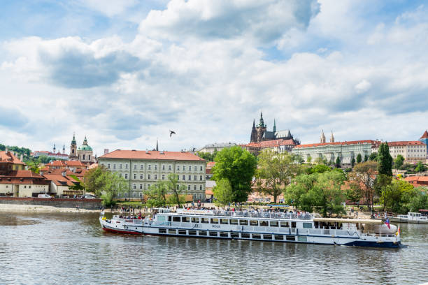 Cruise ship sailing on the Vltava River, with the background of Prague Castle, the world's largest one in the world. stock photo
