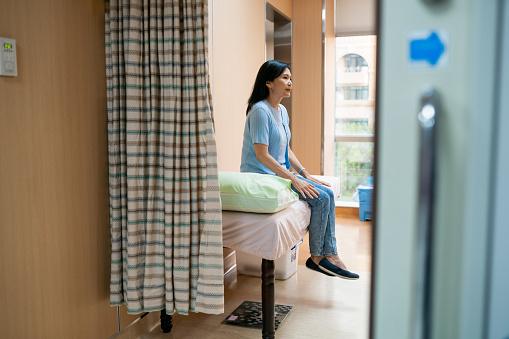 Paciente mujer sentada en la cama en el consultorio del médico photo