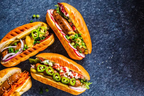 Hot dogs with different toppings on a dark blue background. Fast food concept.