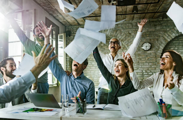 istock Group of playful entrepreneurs having fun while throwing paperwork in the office. 1179735146