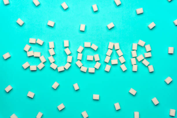 istock The inscription SUGAR made by lump sugar on a colored background. Minimal creative concept 1179735366