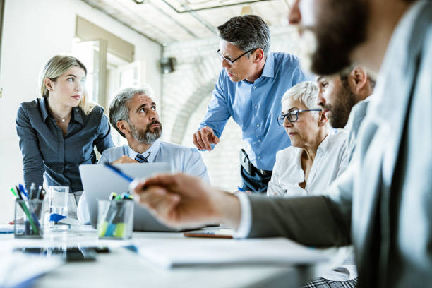 istock Business people talking while working on laptop during a meeting in the office. 1179736627
