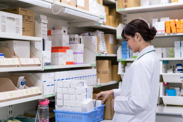 farmacéutico joven organizando medicamentos en el estante - pharmacy medicine pharmacist storage room fotografías e imágenes de stock