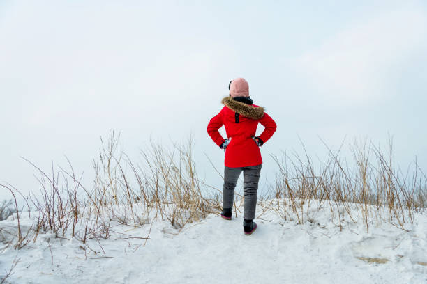 Woman standing on mountain peak with arms akimbo.