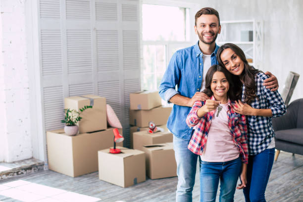 The new page of our story. Delightful parents are hugging their teenage daughter who is holding a key to their new apartment. Delightful parents are hugging their teenage daughter who is holding a key to their new apartment. delightful stock pictures, royalty-free photos & images