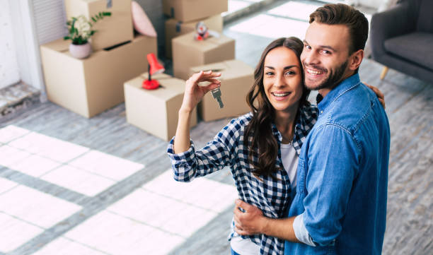 Happy housewarming. A young couple holds happily a key to their new home which they were so excited about, and this can't but make them feel overwhelmed with positive emotions. stock photo