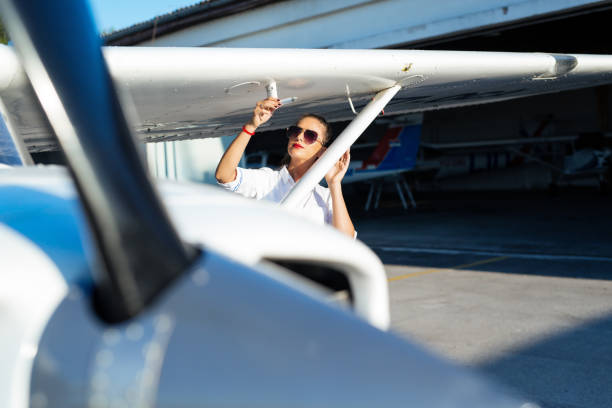 istock Female pilot in sunglasses with modern small aircraft in background 1179737047