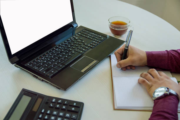 istock A man businessman works behind a laptop and writes in a notebook. On the table are a computer, a calculator and a notebook. Business and work at home. 1179740291