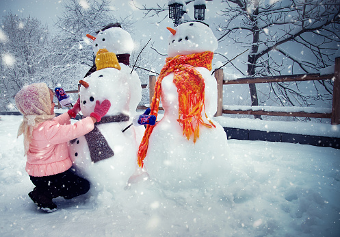 Girl Enjoying Winter and Playing with Snowmen