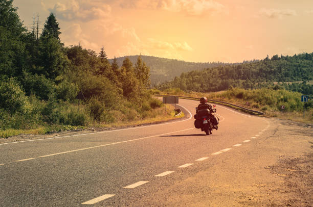 Motorcyclist on mountain road, trip to Ukraine in the Carpathian mountains, beautiful landscape with a road, extreme vacation. Motorcyclist on mountain road, trip to Ukraine in the Carpathian mountains, beautiful landscape with a road, extreme vacation. Random people, photos from the back. carpathian mountain range photos stock pictures, royalty-free photos & images