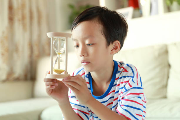 Boy Looking At Hourglass At Home