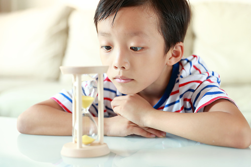 Boy Looking At Hourglass At Home