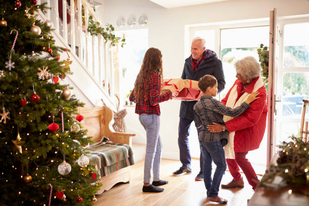 Excited Grandchildren Greeting Grandparents With Presents Visiting On Christmas Day Excited Grandchildren Greeting Grandparents With Presents Visiting On Christmas Day multi generation family christmas stock pictures, royalty-free photos & images