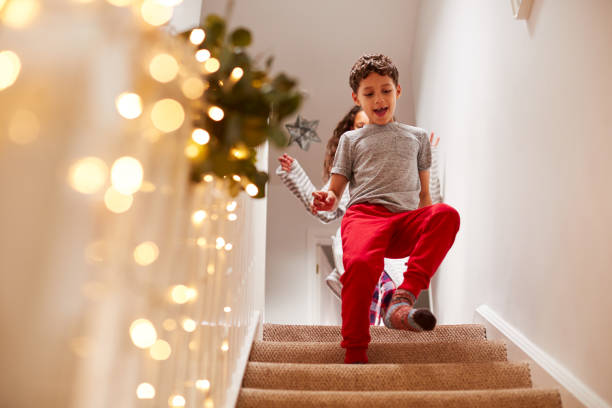 opgewonden kinderen die naar beneden rennen om cadeaus te openen op kerst ochtend - christmas tree stockfoto's en -beelden