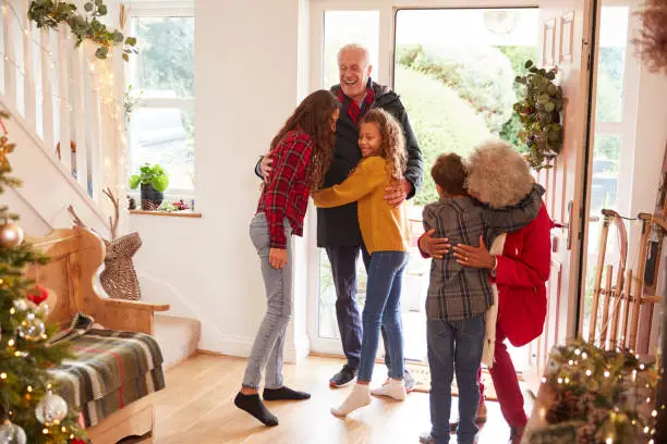 Photo of Excited Grandchildren Greeting Grandparents With Presents Visiting On Christmas Day