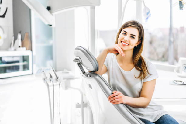 Pretty happy and smiling dental patient sitting in the dental chair at the dental office. stock photo
