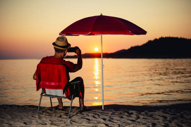 istock Silhouette of man relaxing on the beach at sunset 1179748255