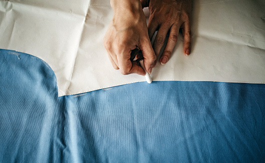 Close up view of Upholsterer's hands sewing leather parts with a sewing machine to fix a seat.