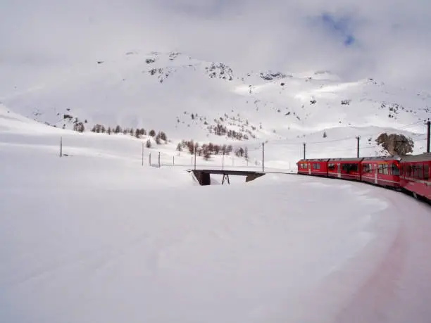 Bernina Express in Winter landscape to St.Moritz during a beautiful sunny day., Switzerland, Europe.