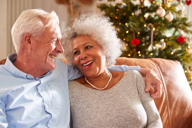 istock Senior Couple Sitting On Sofa With Tree In Background On Christmas Day 1179752345