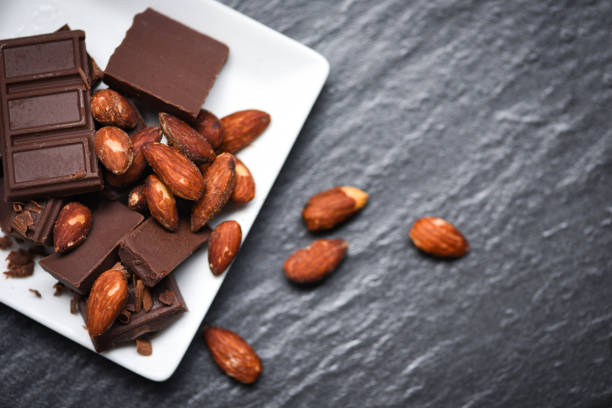 istock chocolate almonds nut on white plate on the dark background - chunks candy sweet dessert and snack 1179753735