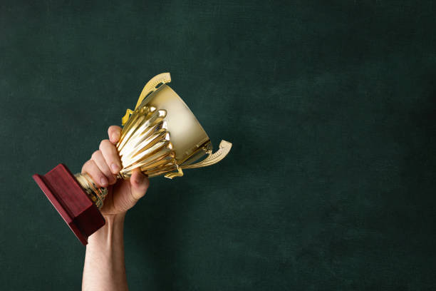 istock Holding up a trophy cup as a winner 1179753900