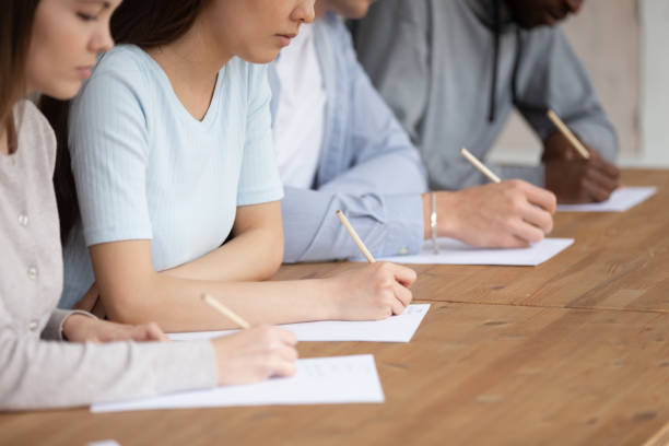 istock Close up mixed race students writing academic test. 1179756349